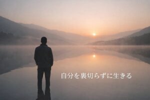 静かな湖畔で朝日を見つめる一人の人物の後ろ姿。水面に映る光と山並みが、内省と静けさを象徴している。